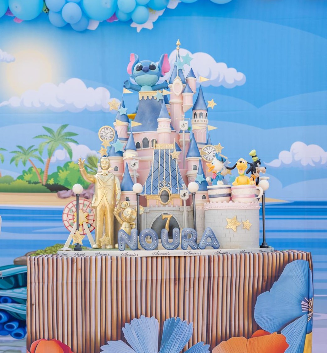 Grand castle-themed birthday cake with ocean backdrop and fantasy details.